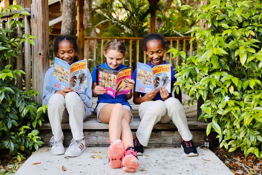 Three Kids Holding New Worlds Reading Books Outside