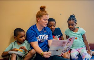 A teacher reading to her students as they all sit on the floor.