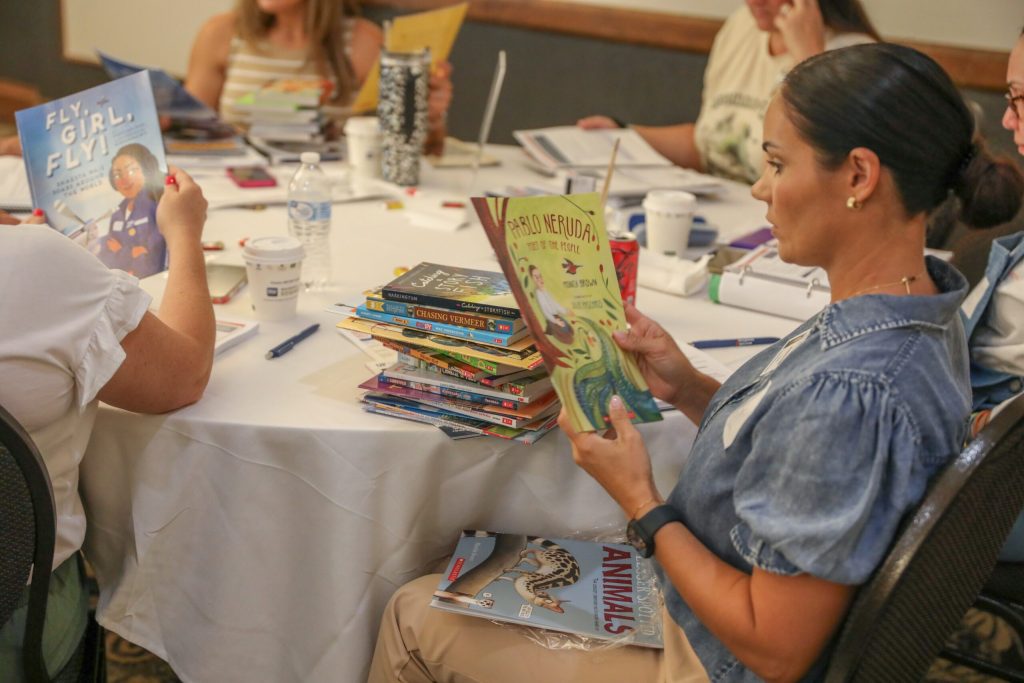 A teacher reads the cover of "Pablo Neruda: Poet of the people" during a New Worlds Reading Teacher Professional Learning Session.