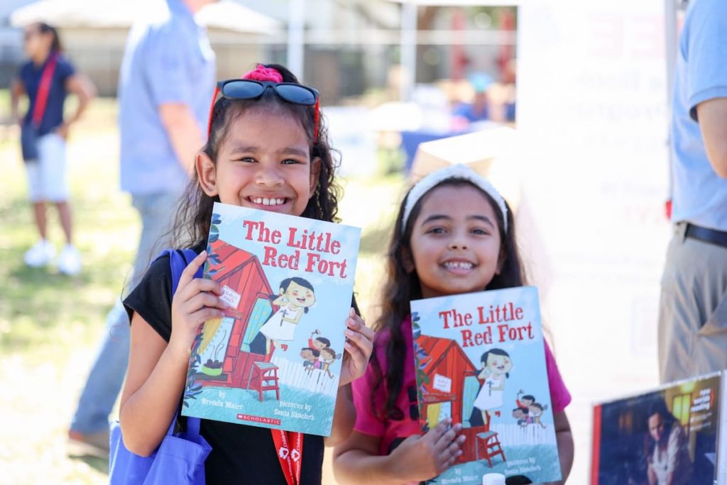 Children holding up books at a New Worlds Reading event
