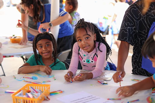Book Bash 2025 Literacy Station Two girls with markers engaging with a literacy-themed gamed station at the 2025 Book Bash in Tampa, Florida.
