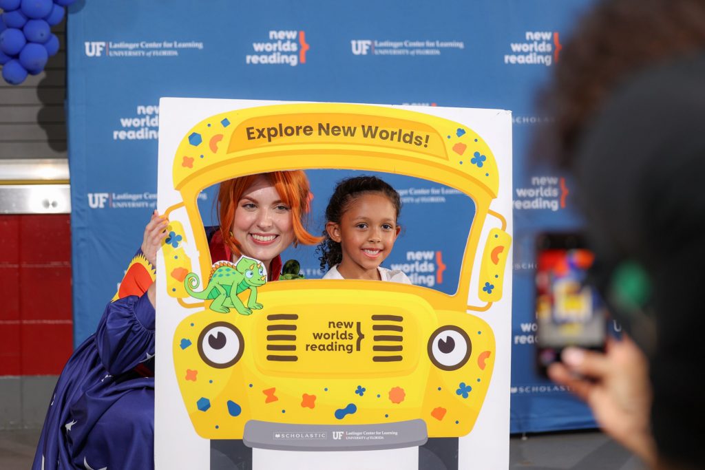 A character actress of Ms. Frizzle taking a photo with a child in the Magic School Bus.