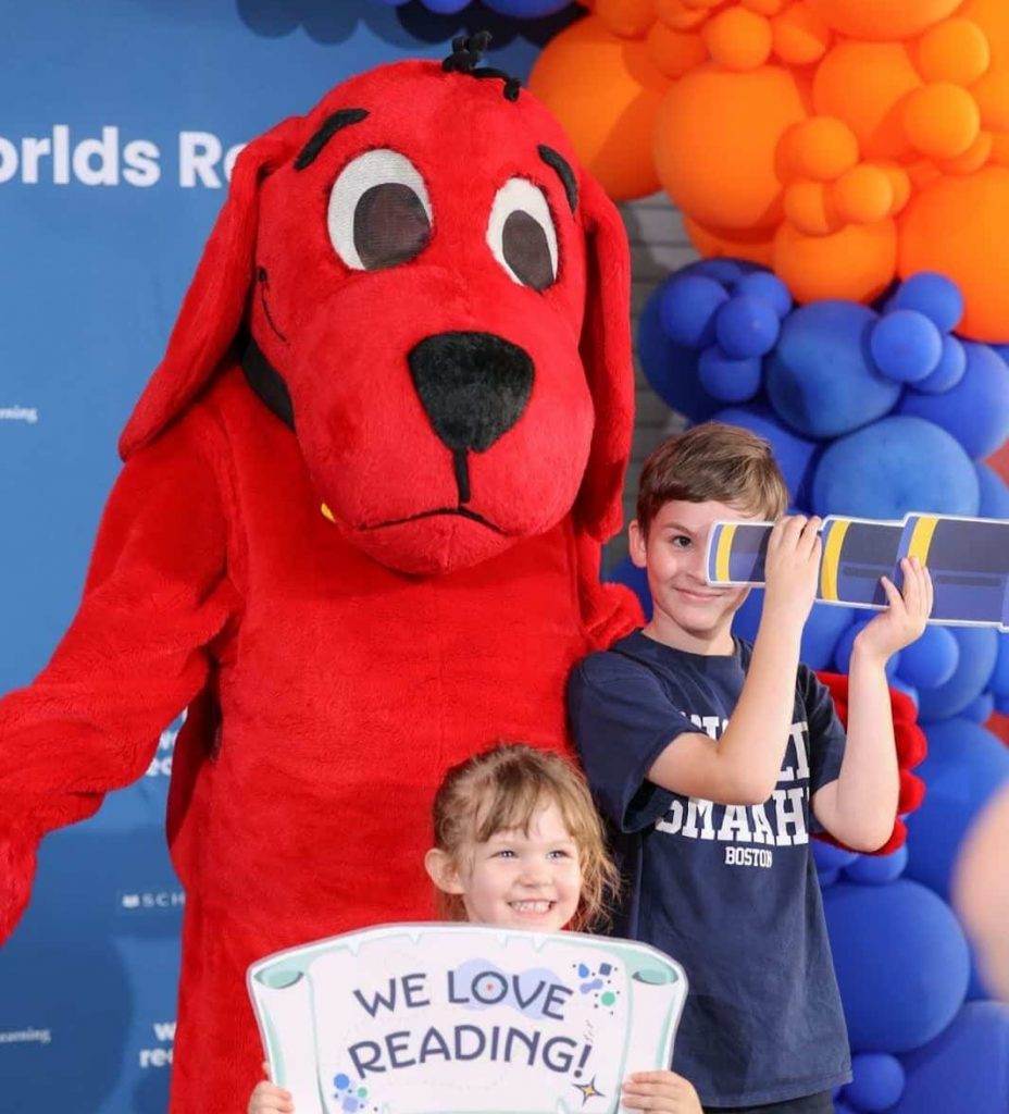 Two children pose with props and Clifford the Big Red Dog,